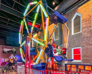 Kids riding an indoor Ferris Wheel at Magic Mini Golf