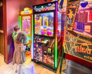 People playing video games and claw toy-grabbing machines at and indoor putt putt place