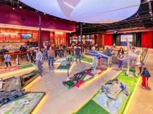 People playing indoor miniature golf